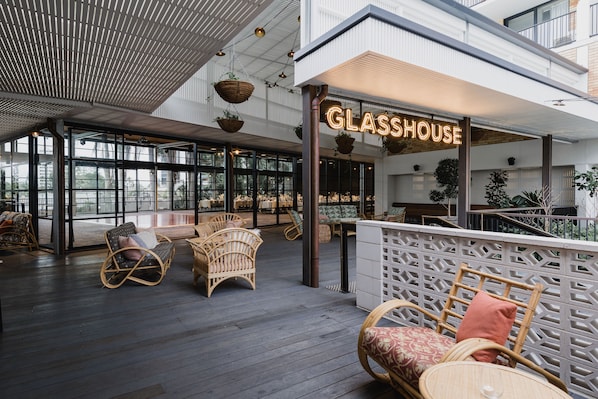 A spacious indoor area with wicker furniture and a sign reading "GLASSHOUSE". - The Island Gold Coast (Surfers Paradise)
