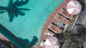 An aerial view of a pool area with lounge chairs and umbrellas, surrounded by a brick walkway. - The Island Gold Coast (Surfers Paradise)