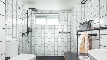 Une salle de bain moderne avec des carreaux noirs et blancs, des toilettes, un lavabo et un espace douche.