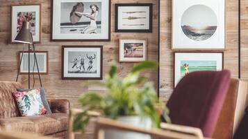 Una sala de estar con pared de madera, un sofá de cuero, un sillón rojo y una mesa de centro con una planta.