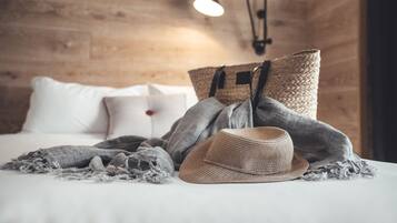 Una cama hecha con cuidado, con un sombrero de paja y un bolso tejido encima.