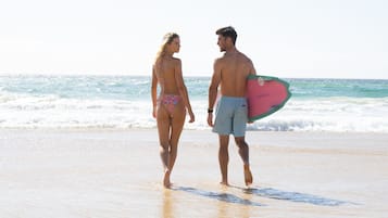 Una pareja caminando sobre la playa con el océano al fondo.