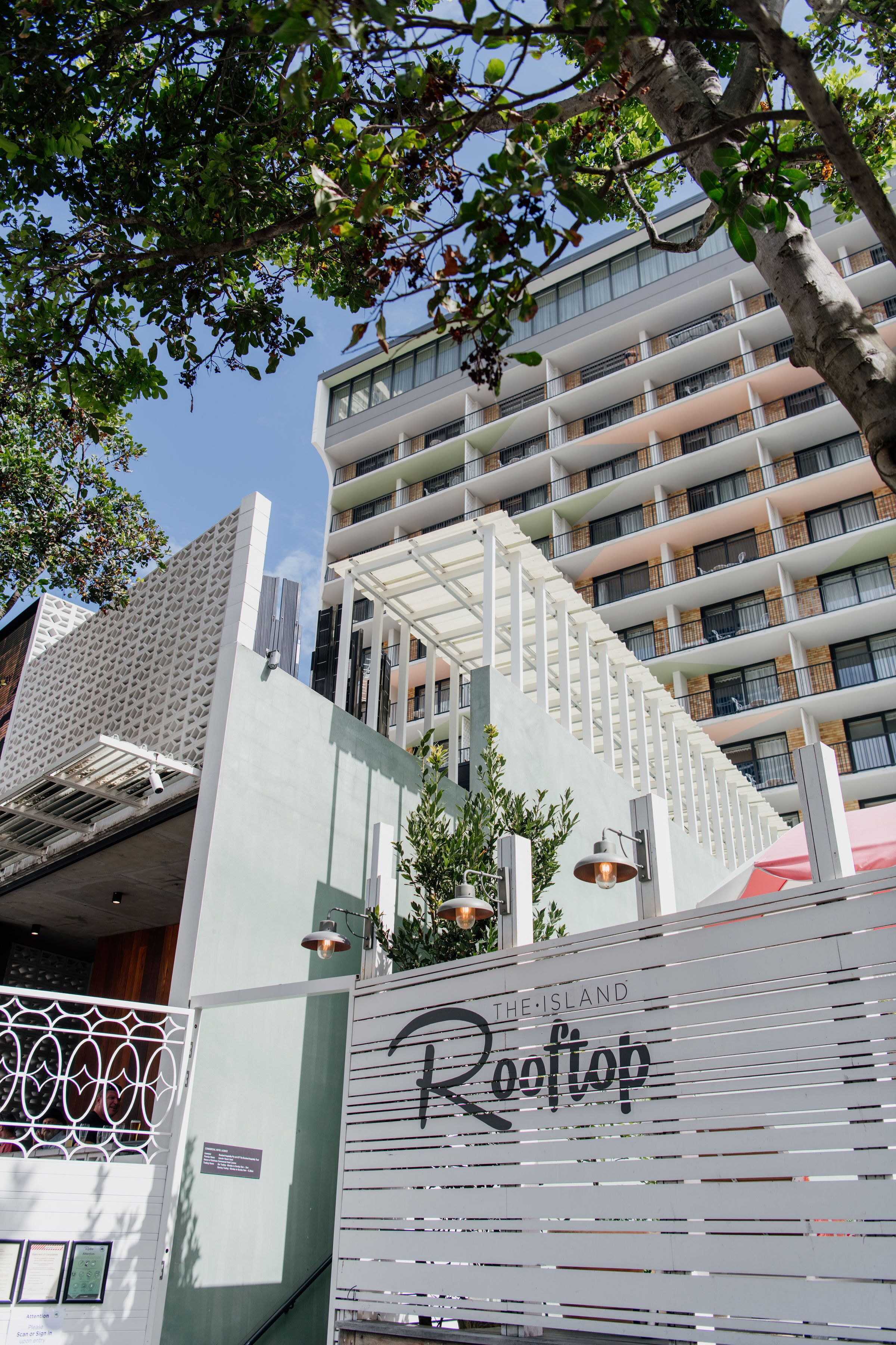 Um edifício moderno com várias varandas e uma placa com a inscrição 'The Island Rooftop'.