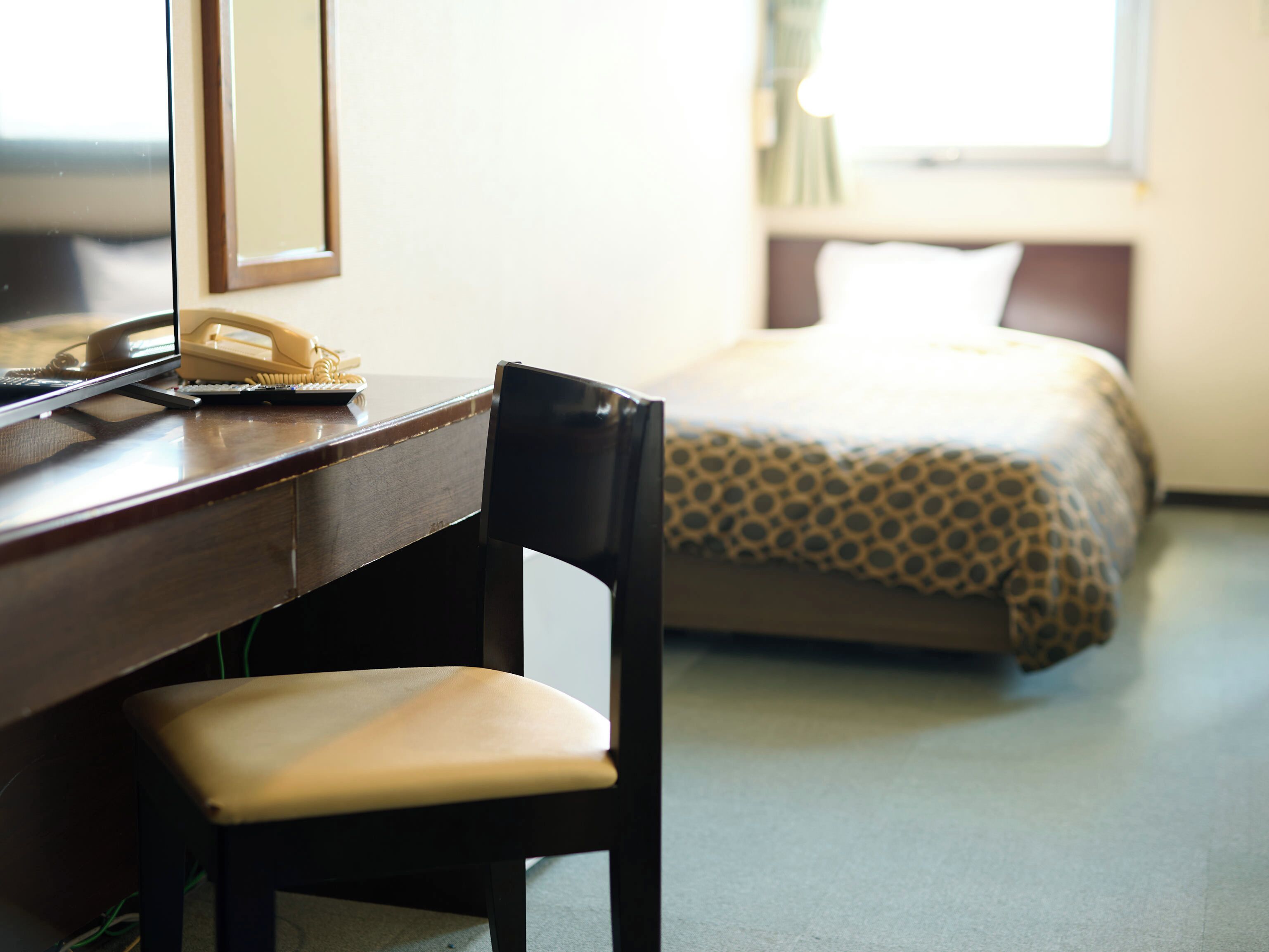 Una habitación de hotel con escritorio, silla y cama con cubrecama estampado.