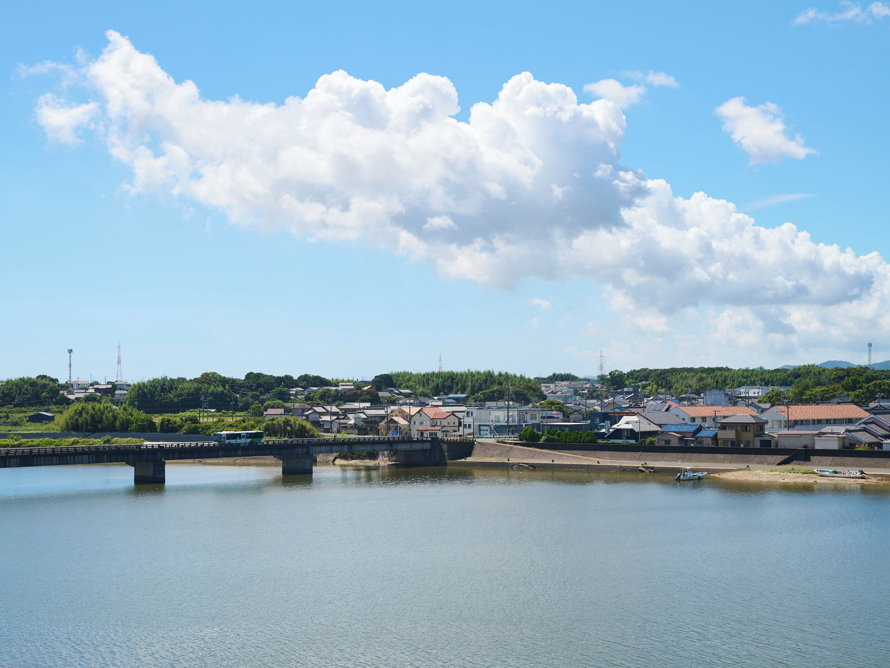 A river with a bridge, houses, and a clear sky.
