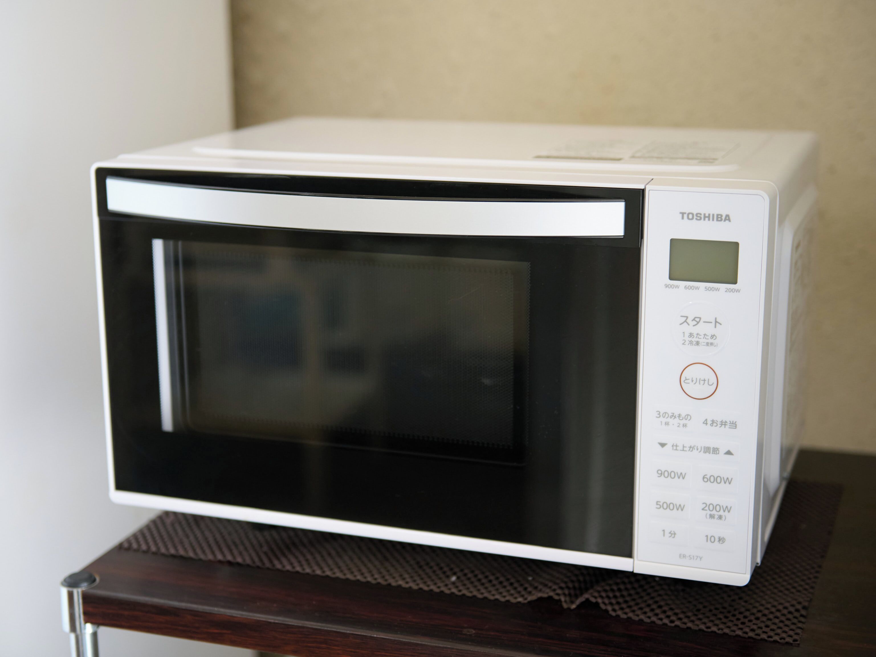 A white Toshiba microwave on a dark wooden table.