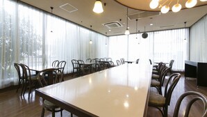 A conference room with a long table, multiple chairs, and hanging lights. - Okadaya Toyohashi (Toyohashi)