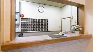 A reception desk with a clock, a phone, and a plant. - Okadaya Toyohashi (Toyohashi)