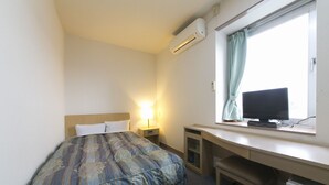 A hotel room with a bed, a desk with a computer, a window with curtains, and an air conditioning unit. - Okadaya Toyohashi (Toyohashi)