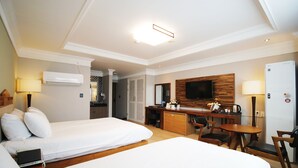 Une chambre d’hôtel avec deux lits, un bureau, une télévision et un réfrigérateur.