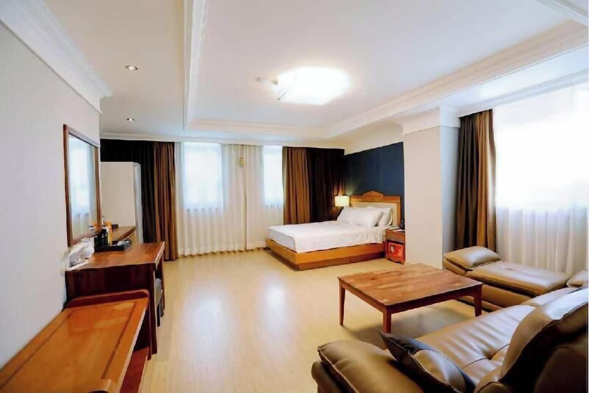 Quarto de hotel com cama, escrivaninha, sofá e mesa de centro.