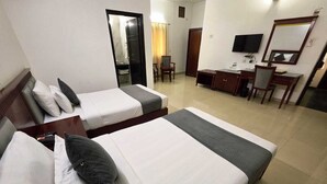 Una camera d'albergo con due letti, una scrivania, una sedia, una televisione e uno specchio.