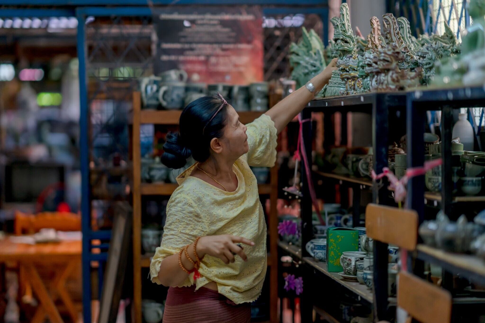 A person reaching for a decorative item on a shelf in a store.