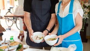 A table with various food items and two people holding bowls. - Sukhothai Garden (Sukhothai)