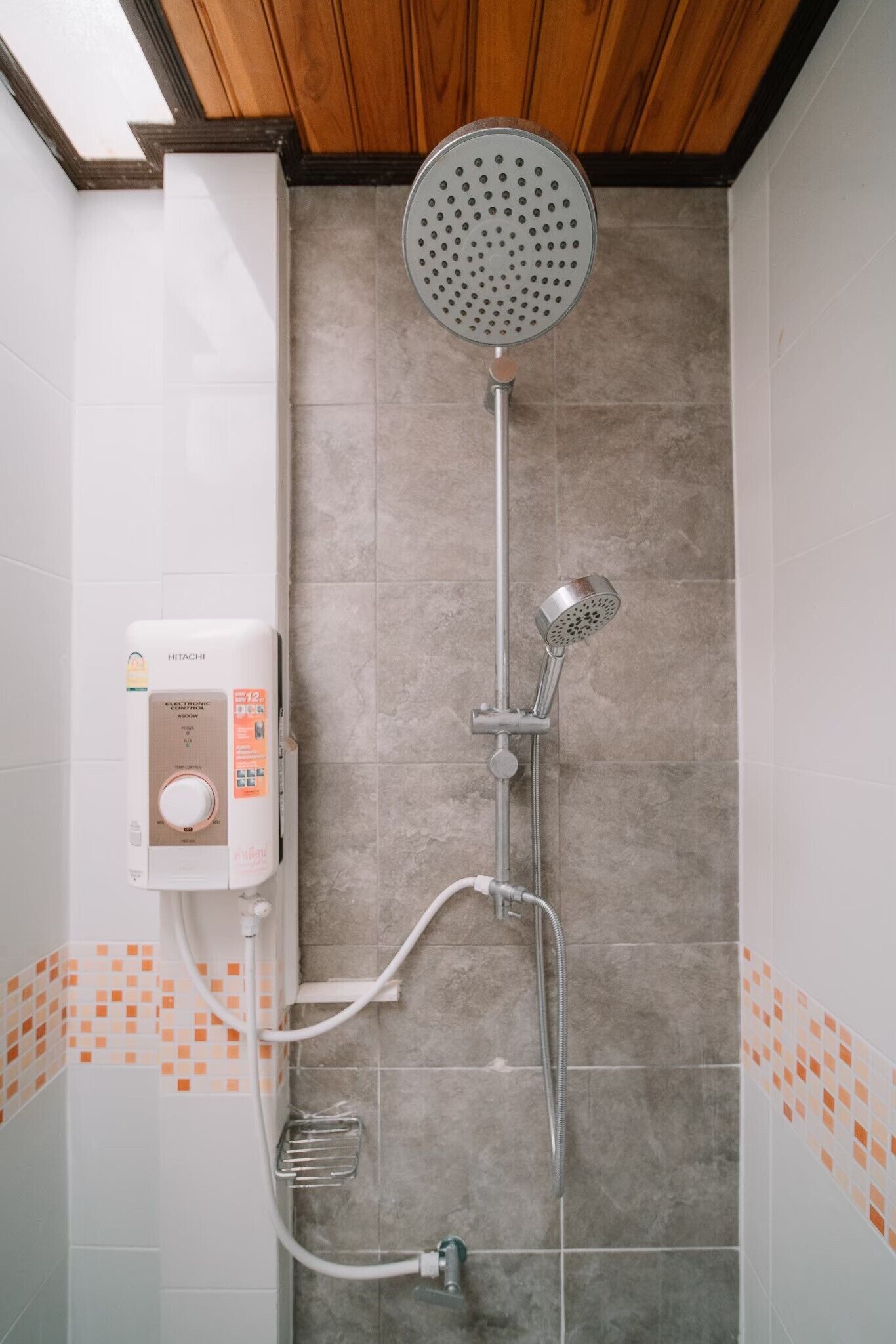 A shower with a handheld showerhead, a wall-mounted control panel, and a handheld showerhead.