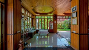 A spacious lobby with wooden paneling, a central seating area, and a Coca-Cola refrigerator. - Sukhothai Garden (Sukhothai)
