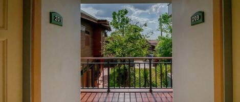 A corridor with doors labeled 201 and 209 leading to a balcony with a view of trees and buildings.
