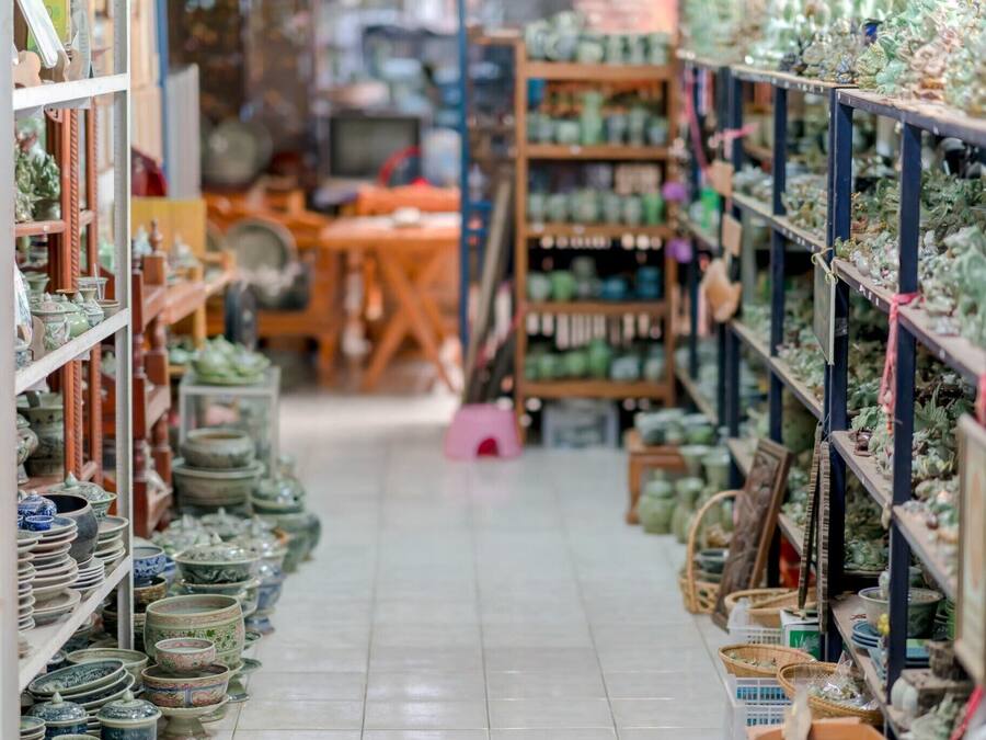 A narrow aisle in a store with shelves on both sides displaying various ceramic items.