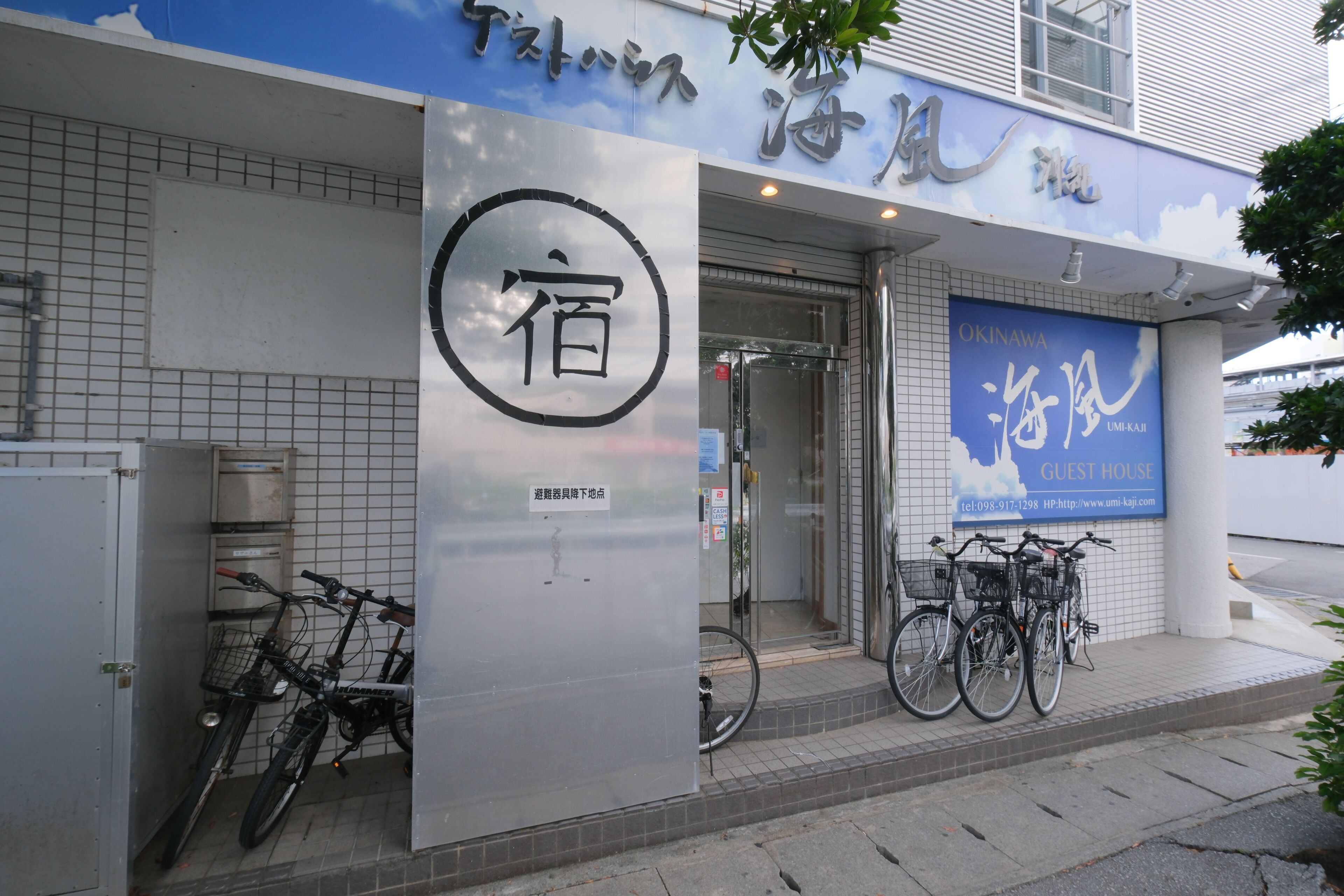 Ein Hotel Eingang mit einem Schild auf Japanisch, einem Fahrradständer und einer Anzeige für ein Gästehaus.