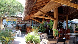 An outdoor seating area with tables and chairs, surrounded by potted plants. - Khlong Dao Sunset Villa (Ko Lanta)