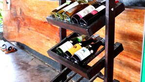 A wooden wine rack with multiple bottles, a sign reading "World of Wines Selection," and a rustic backdrop with a woven structure. - Khlong Dao Sunset Villa (Ko Lanta)