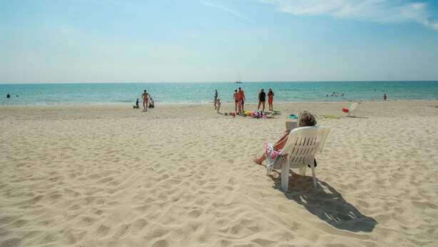 A sandy beach with people and a sailboat in the distance. - Khlong Dao Sunset Villa (Ko Lanta)