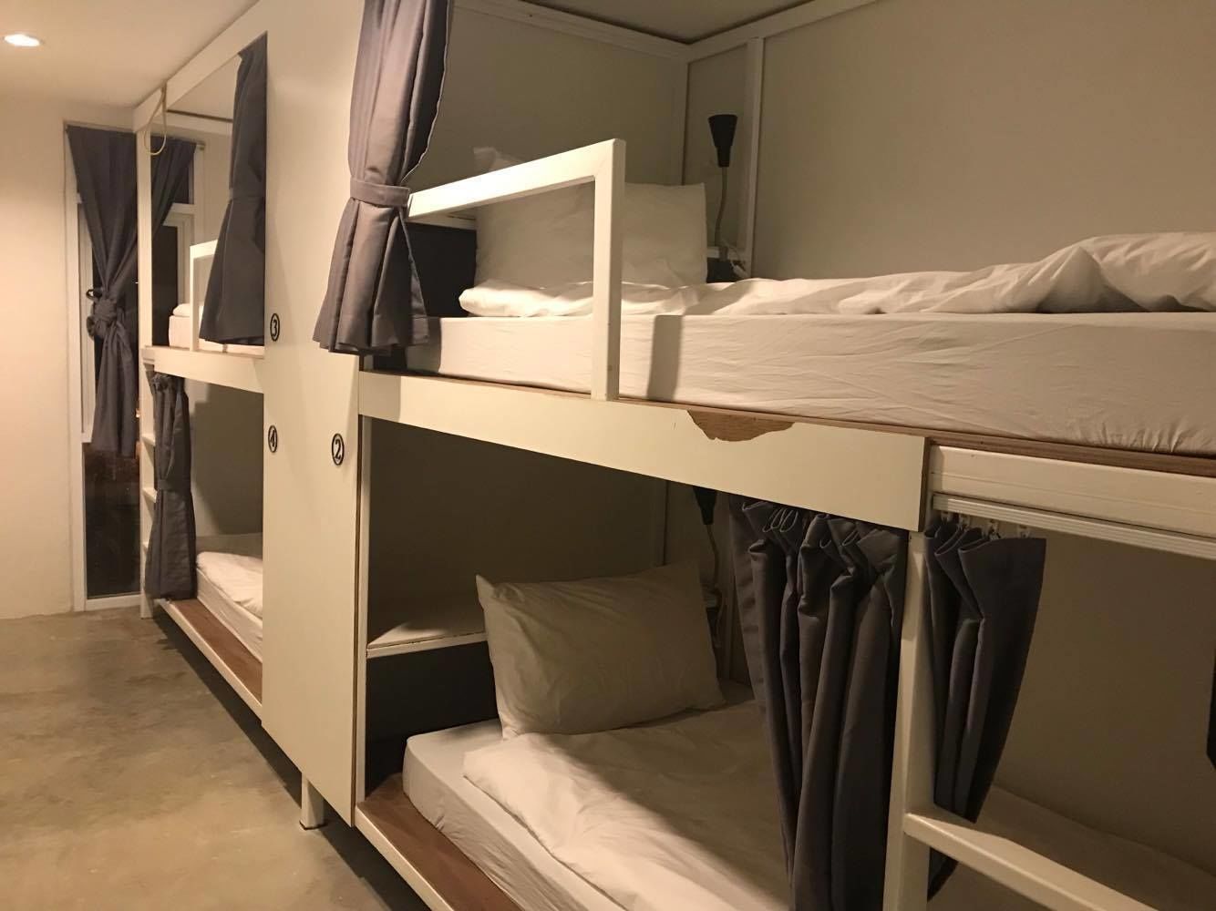 A bunk bed room with curtains, a mirror, and a bedside table.