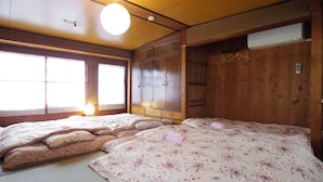 A traditional Japanese-style room with tatami flooring, a wooden wardrobe, and a bed with floral bedding. - Oyado Sanjo Machiya (Kyoto)