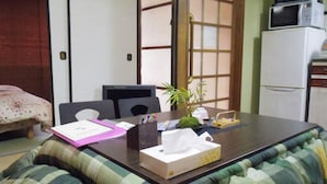 A room with a bed, a desk with a computer, a small plant, and a microwave. - Oyado Sanjo Machiya (Kyoto)