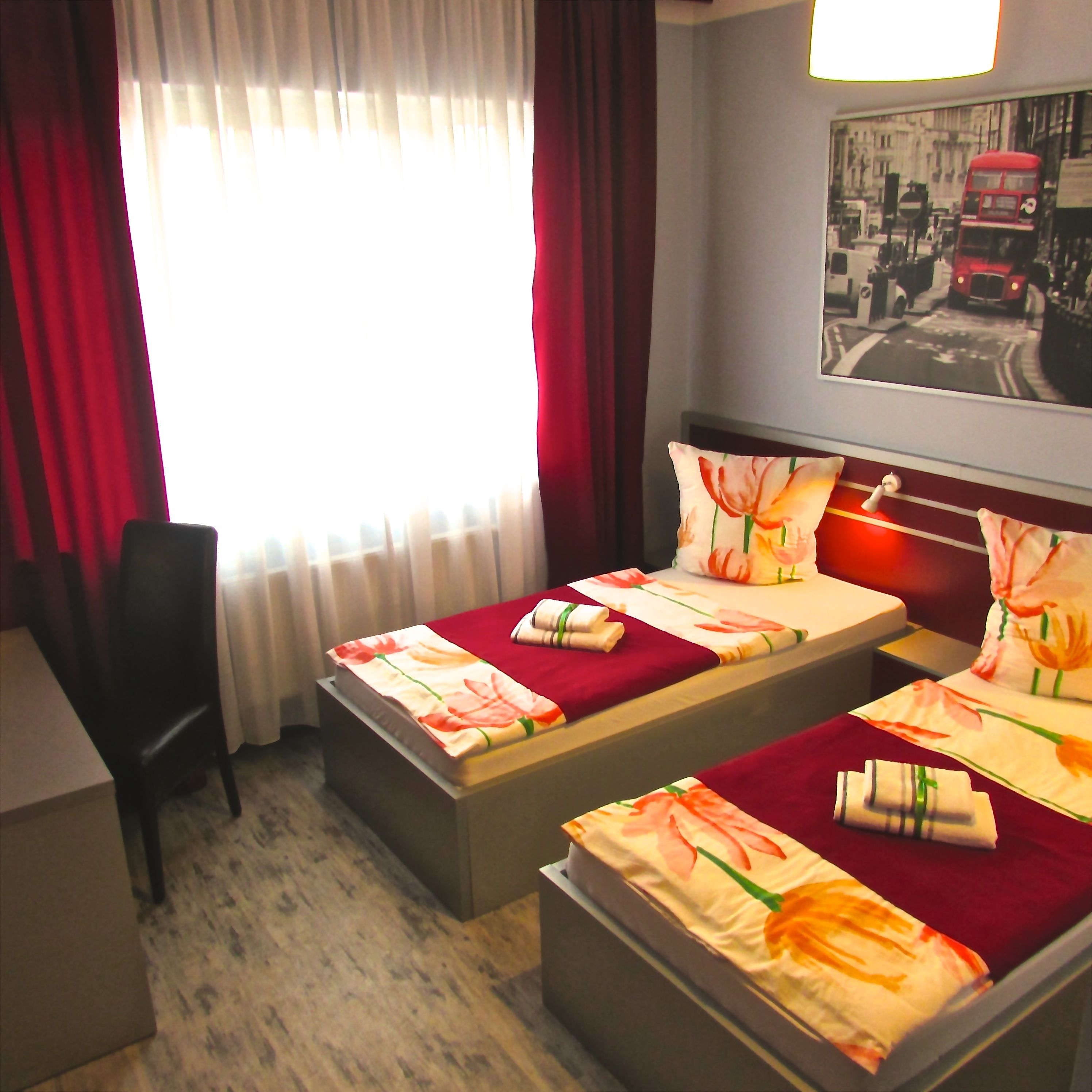 A hotel room with two beds, a desk, and a chair.