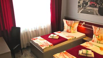 A hotel room with two beds, a desk, and a chair.