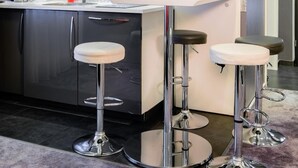 Een moderne keuken met een bar, roestvrijstalen apparatuur en een klok aan de muur.