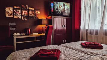 Una habitación de hotel con cama, escritorio, televisor y una cortina roja.