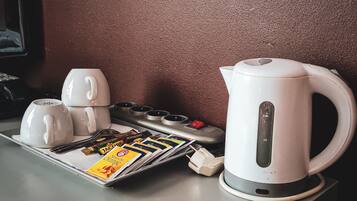 Una estación de café con una tetera, tazas y una bandeja de revistas.