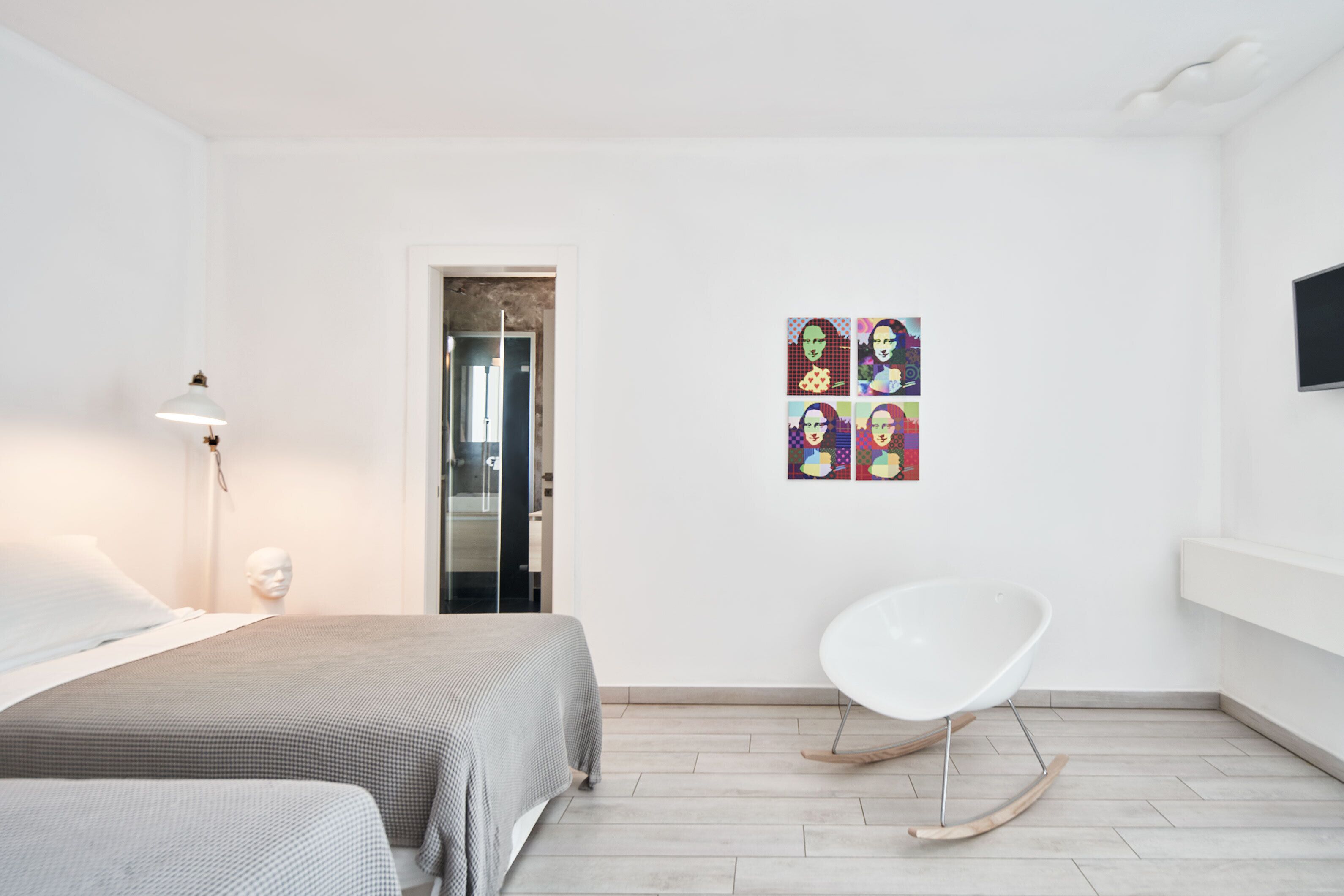 A modern hotel room with a bed, a chair, and a wall-mounted TV.