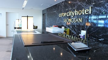 A modern reception desk with a marble wall and the text "coop cityhotel SEONGSAN".