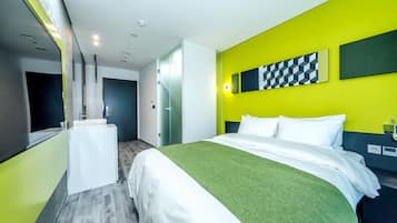 Una habitación de hotel moderna con una cama, un escritorio pequeño y una pared de color amarillo brillante.