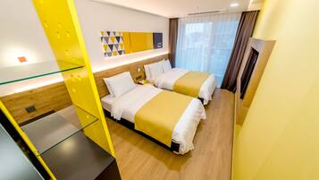 A hotel room with two beds, a glass partition, a wooden floor, and a modern decor with yellow accents.