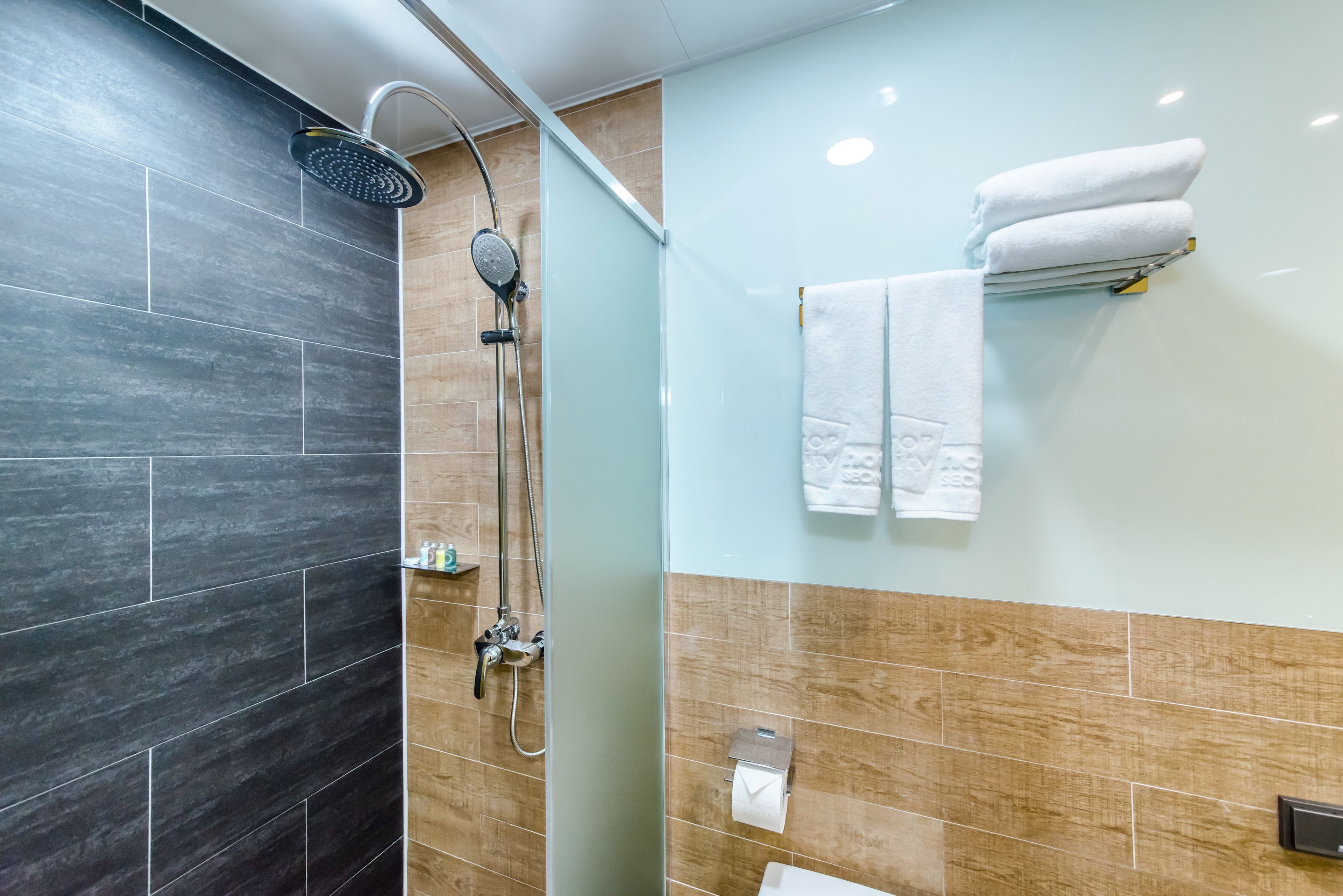 A modern bathroom with a shower, a toilet, and a towel rack.