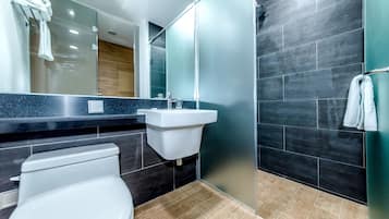 A modern bathroom with a toilet, sink, and glass shower enclosure.