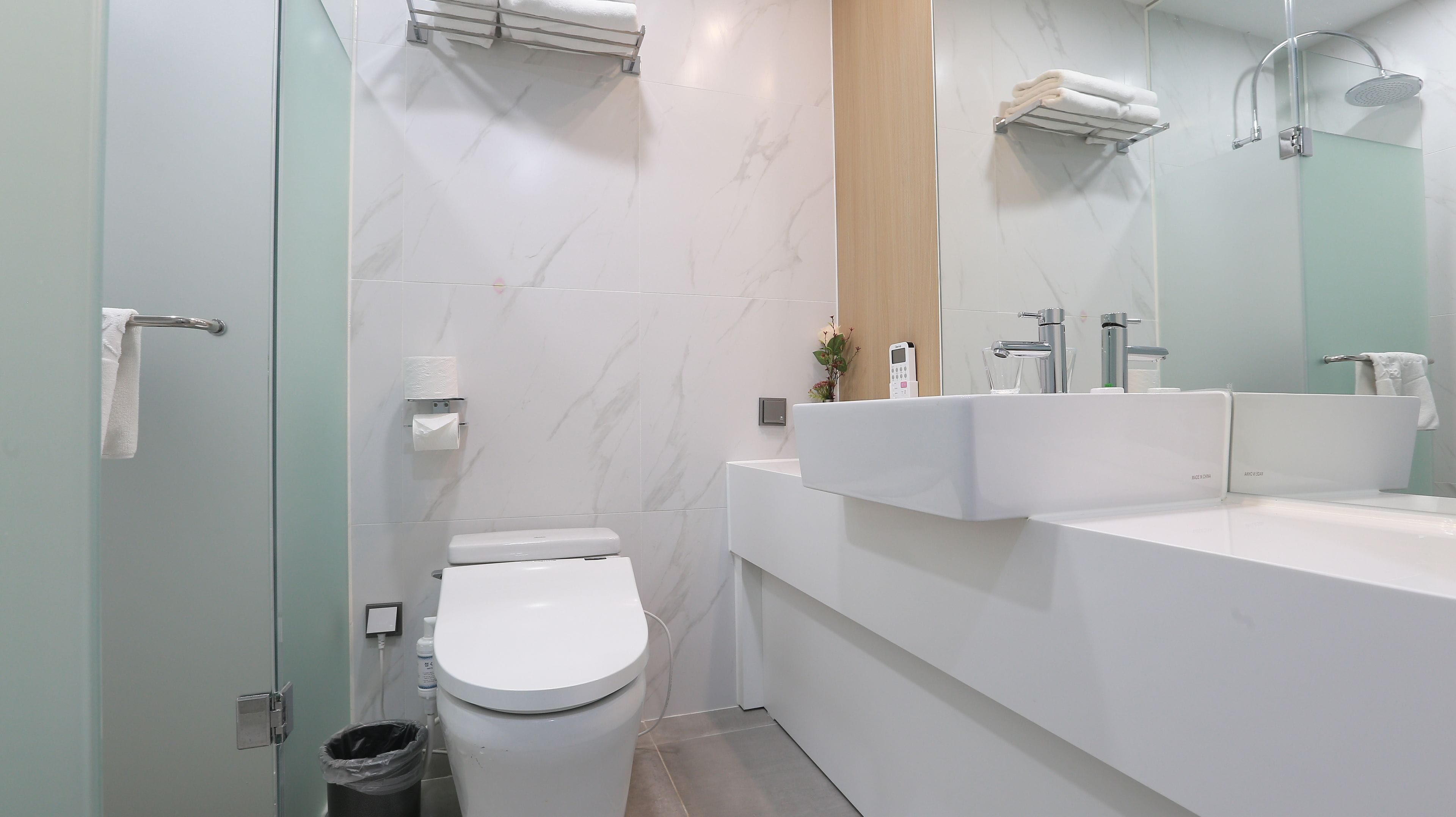 A modern bathroom with a toilet, bidet, sink, and mirror.