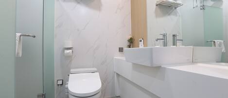 Ein modernes Badezimmer mit Toilette, Bidet, Waschbecken und Spiegel.