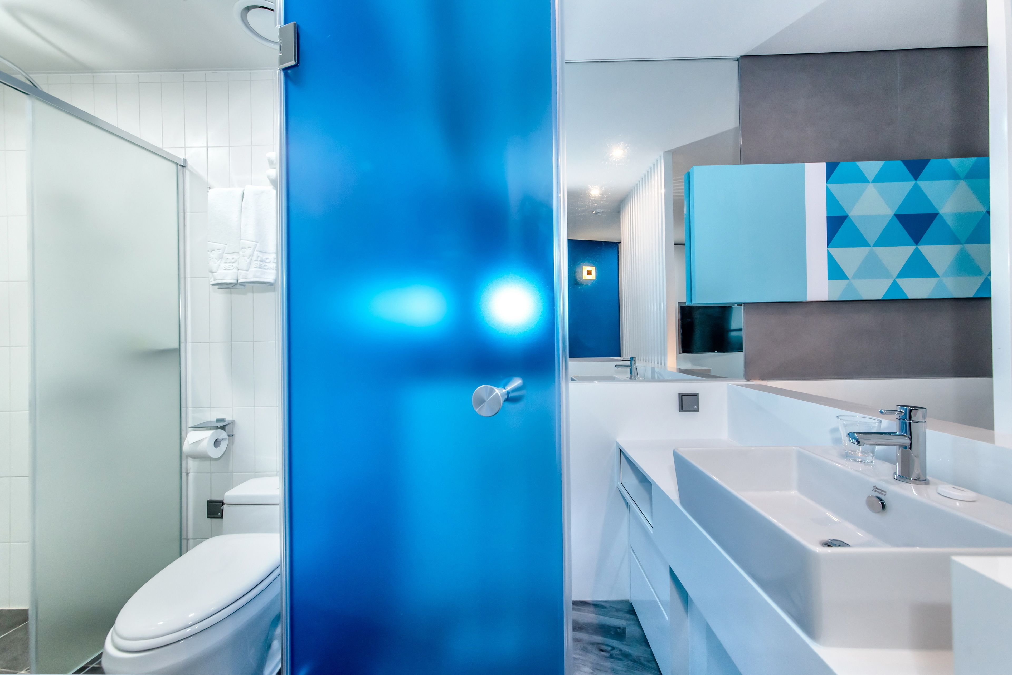 A modern bathroom with a glass shower enclosure, a white toilet, and a large sink with a mirror above it.