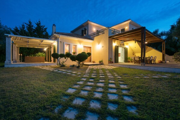 Una casa moderna con un porche cubierto, un césped cuidado y un sendero de piedra que conduce a la entrada.