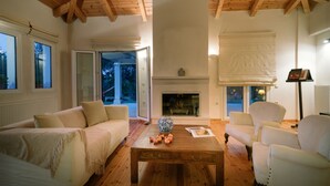 Una sala de estar acogedora con chimenea, vigas de madera en el techo y un ventanal grande.