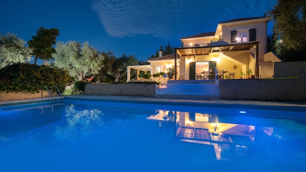 Una casa de dos pisos con piscina al frente.