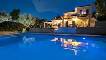 A two-story house with a swimming pool in the foreground.