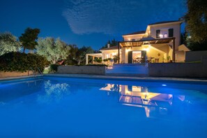 Ein zweistöckiges Haus mit einem Schwimmbecken im Vordergrund.