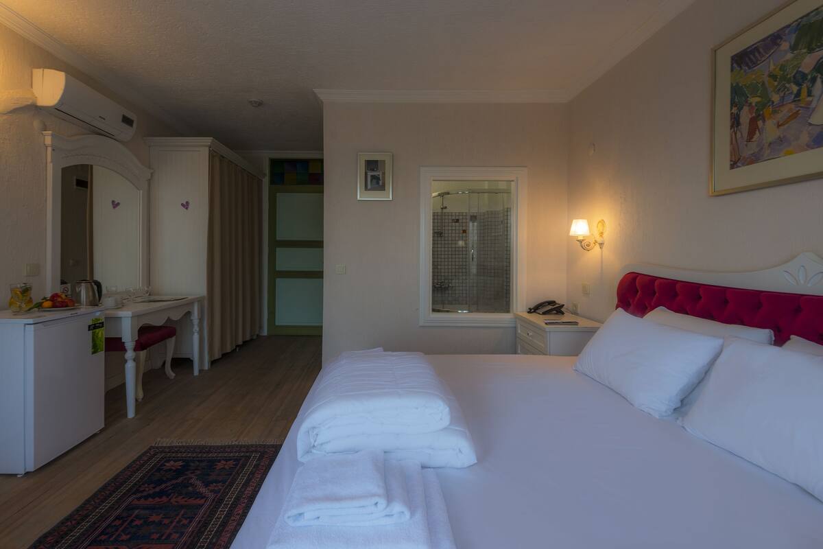 Una habitación de hotel con una cama, un escritorio, una silla y zona de ducha.