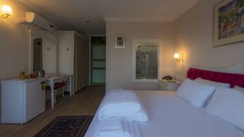 A hotel room with a bed, a desk, a chair, and a shower area.